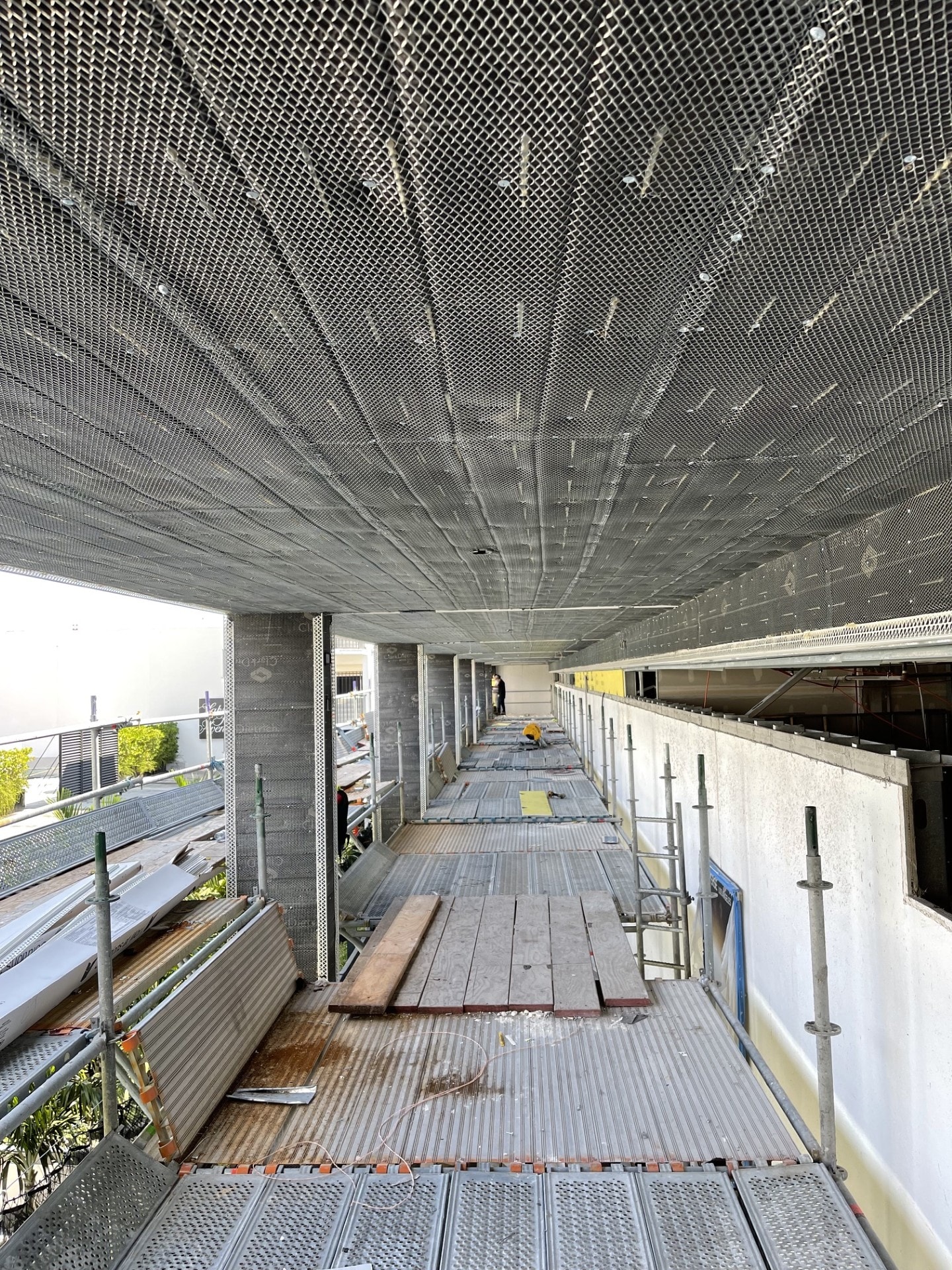 Metal mesh ceiling installation on scaffolding walkway