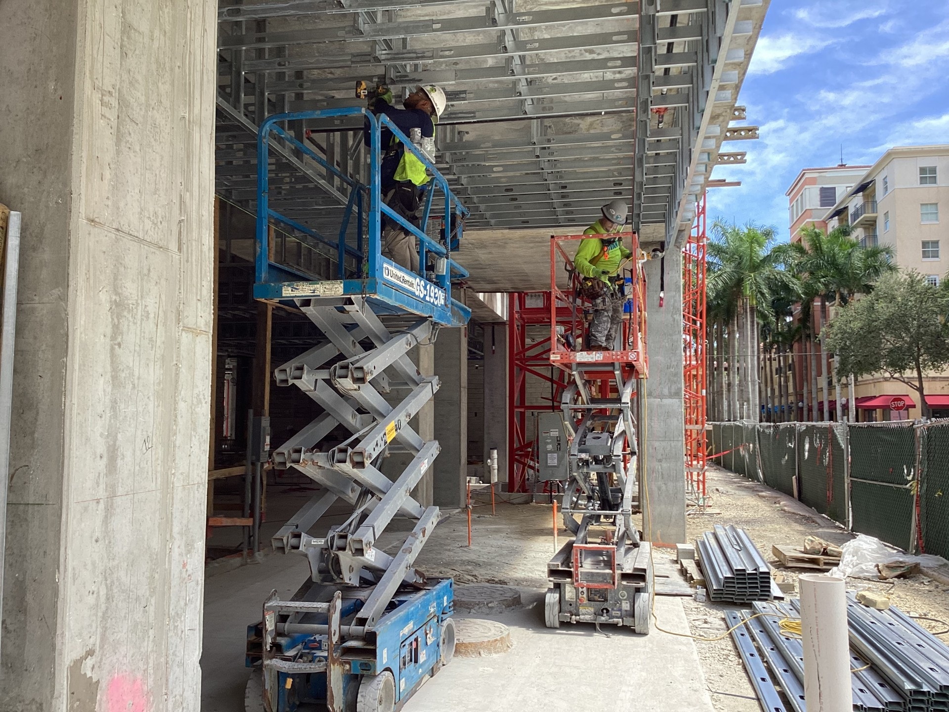 Two workers on scissor lifts installing ceiling framing
