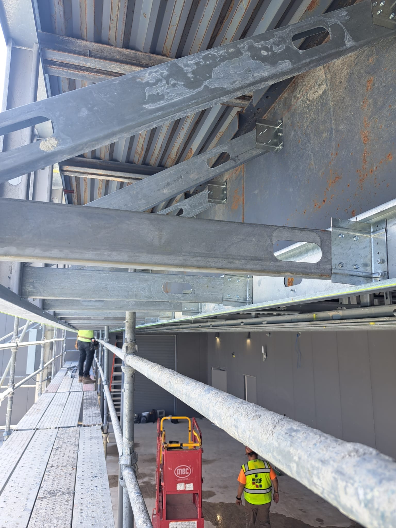 Large steel beam framing with crew on scaffolding and MEC lift