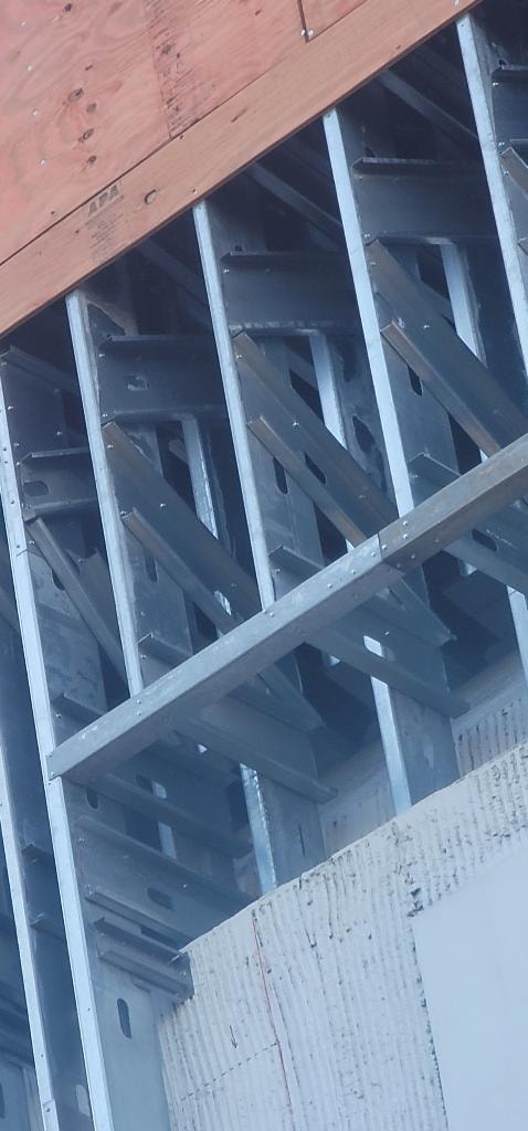 Close-up of steel stud framing with wood sheathing above