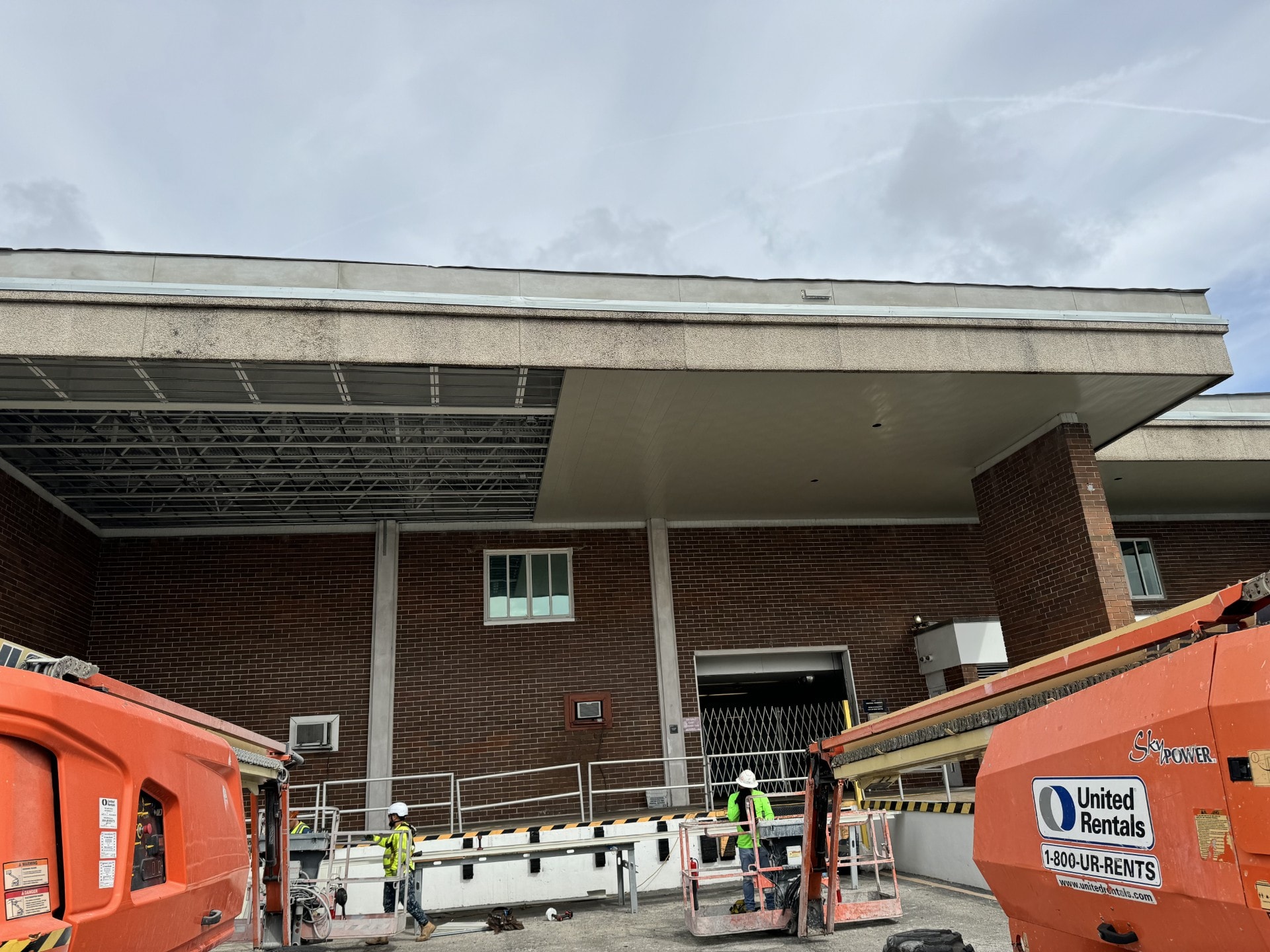 Stucco canopy and soffit on brick commercial building with crew and lifts