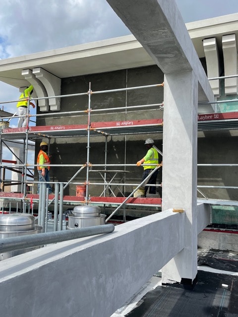 Crew on scaffolding applying stucco on rooftop level