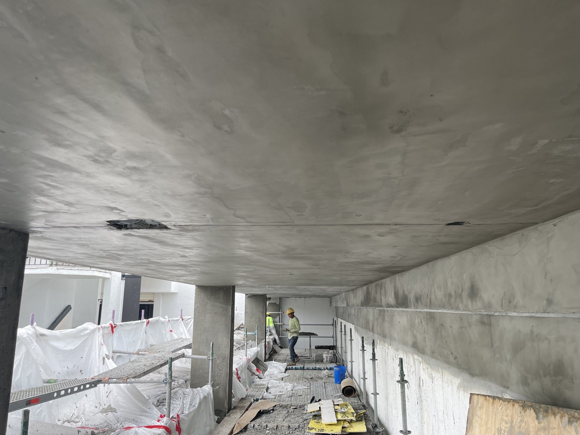 Worker plastering stucco soffit and walls under structure
